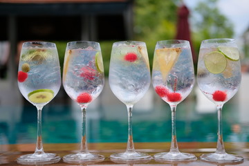 gin and tonic cocktails with fruit in wine glass on wooden table