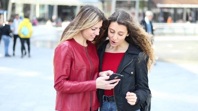 Two female friends looking at a smartphone and smiling