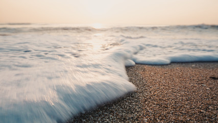 Tropical beach with wave,blue sky on golden beach sand in sunset light