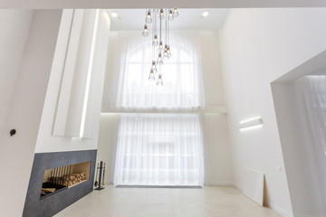 Fototapeta na wymiar huge chandelier near fireplace for bright interior loft in front of a large panoramic window