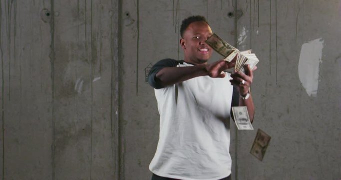 Portrait of a young smiling African American throwing money over gray background with money rain