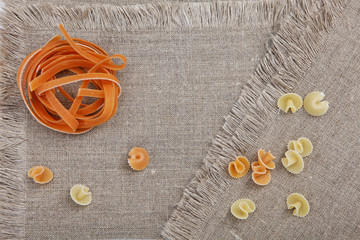 Pasta nest orange color on a napkin. View from above. Still life concept.