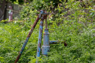 Vintage rusty water fountain hand pump in russian village. Abandoned water wellhead.