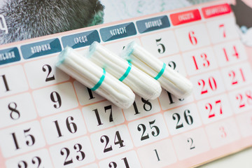 The concept of critical days, menstruation. Tampons on the calendar grid.