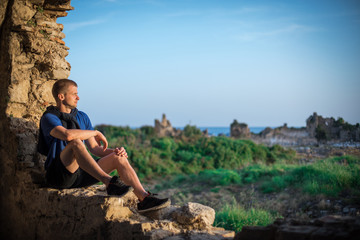 Fototapeta na wymiar Man is sitting at the ruins of an ancient city, Side, Turkey