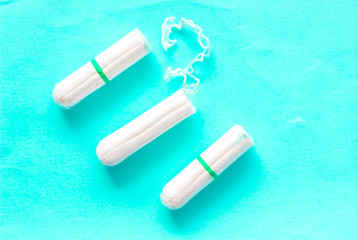The concept of critical days, menstruation. Isolated tampons on turquoise background, close-up.