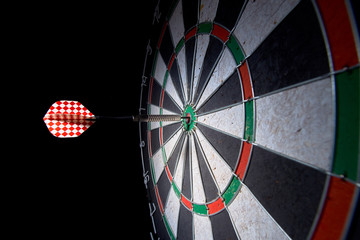 darts board on a black background. 1 dart in the center