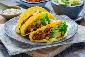 Smoky Mexican pork and bean tacos with lettuce and avocado salad