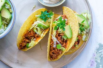 Smoky Mexican pork and bean tacos with lettuce and avocado salad