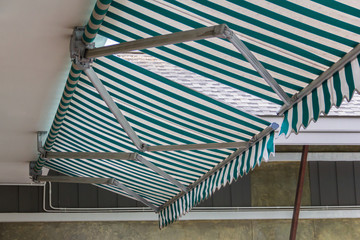 green and white striped awning with asphalt roof background.