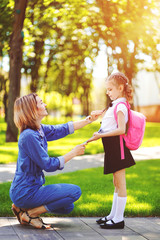 First day at school. mother leads a little child school girl in first grade. Woman and girl with backpack behind the back. Beginning of lessons. First day of fall