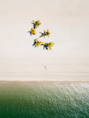 Aerial view of bride and groom lying on white sand beach with green palm trees near the sea, Langkawi, Malaysia.