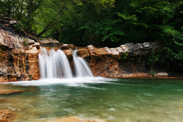 Very beautiful spring waterfall in the valley of the river Jean in the forest