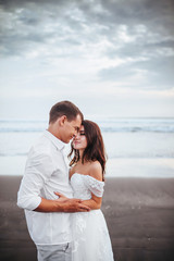 Elegant gorgeous bride and groom walking on ocean beach during sunset time. Romantic walk newlyweds on tropical island. Concept marriage, just married
