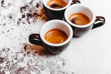 Three cups of freshly brewed espresso coffee on a textured table top with copyspace