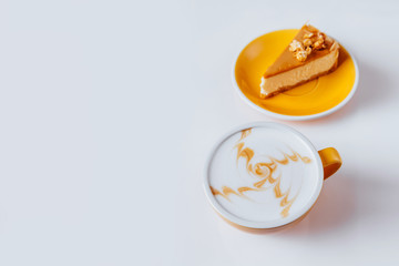 Cup of hot cappuccino coffee with cake on white table with copy space