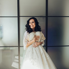 Bride in white luxury dress is getting ready for wedding. Morning preparations. Woman putting on dress.