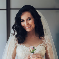 Bride in white luxury dress is getting ready for wedding. Morning preparations. Woman putting on dress.