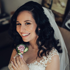 Bride in white luxury dress is getting ready for wedding. Morning preparations. Woman putting on dress.