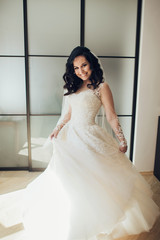 Bride in white luxury dress is getting ready for wedding. Morning preparations. Woman putting on dress.