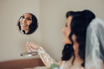 Bride in white luxury dress is getting ready for wedding. Morning preparations. Woman putting on dress.