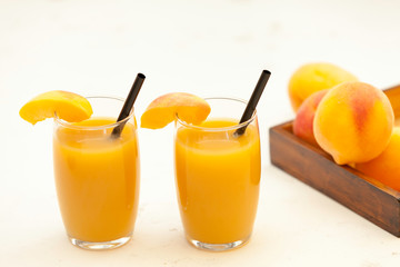 two peach juice glasses  and  peaches of wooden basket