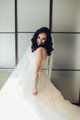 Bride in white luxury dress is getting ready for wedding. Morning preparations. Woman putting on dress.