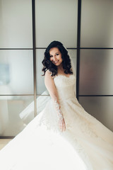 Bride in white luxury dress is getting ready for wedding. Morning preparations. Woman putting on dress.