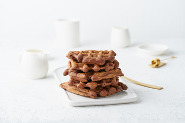 Chocolate banana waffles on white table. Scandinavian minimalist style, side view