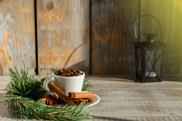 White cup with coffee beans stands on a wooden table. Autumn vibes. Christmas decorations