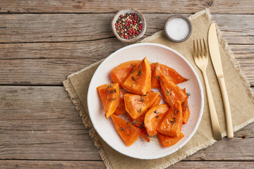 roasted pumpkin, pieces in plate with honey and seasonings, old rustic wooden dark table, copy space