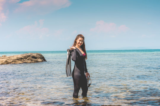 Vacations Of Attractive Asian Woman Wearing Wetsuit And Holding Diving Equipment Fins And Mask Standing On Seashore Smile Feeling So Happiness And Relax Ready To Dive,recreational Diving Concept