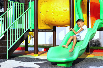 Happy kids concept, a boy playing on slide toy at the playground. 