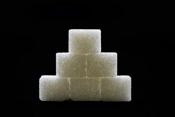 Sugar cubes lined up in pyramid shape. Black background