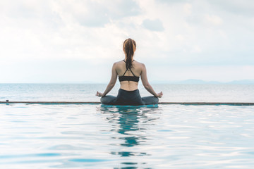 Vacation of Beautiful Attractive Asian woman relaxing in yoga lotus pose on the pool above the beach with beautiful sea in Tropical island,Feeling comfortable and relax in holiday,Vacations Concept
