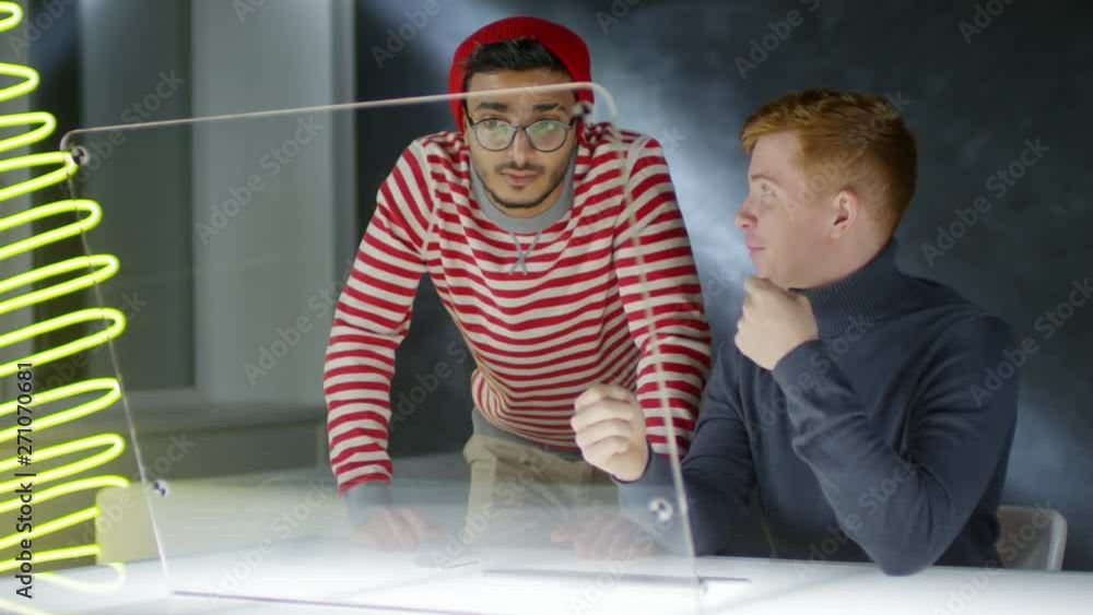 Aufkleber medium shot of young caucasian man and arab man standing nearby swiping on invisible display of futu
