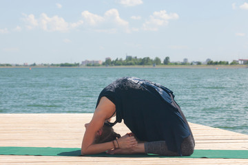 Beautiful woman practicing Yoga by the lake