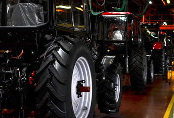 Fototapeta premium Tractor Manufacture work. Assembly line inside the agricultural machinery factory. Installation of parts on the tractor body - Image