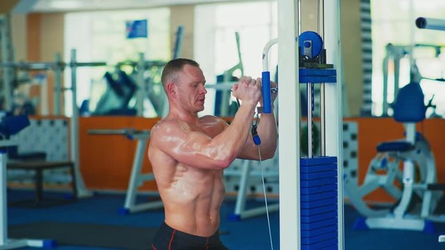 Bodybuilding concept. Muscular man doing cable rope triceps pull up exercise while working out in gym