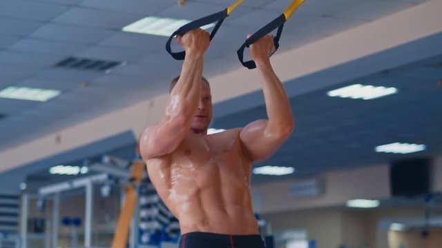 Exercise at a gym. Strong man training with trx in a gym