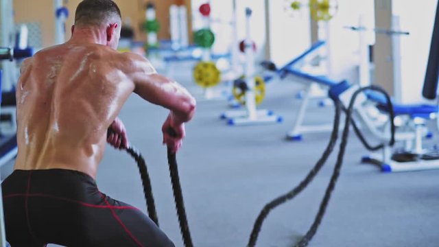 Athlete with ropes in gym. High-intensity interval training. Slow motion