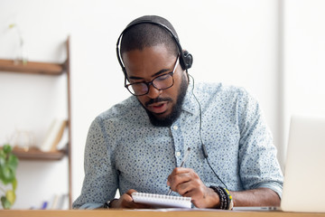 African American man in headphones taking E-learning course at office - obrazy, fototapety, plakaty