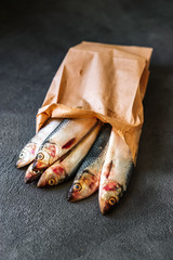 Raw herring in eco paper bag on a dark background