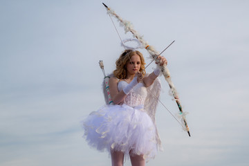 Cute teen cupid on the cloud - sky background. Lovely and cute youth. Lovely girl cupid with bow...