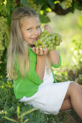 Child girl with grapes. Gathers fruit. 