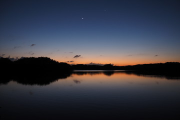 The Moon and Venus over an exceptionally calm Paurotis Pond in Everglades National Park, Florida in late twilight.