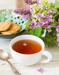 Tea and blooming lilac, petal in a cup
