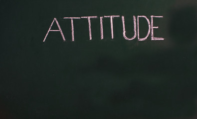 Attitude word written on green board with chalk stick