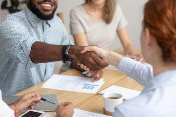 Obraz premium Close up male and female diverse business people handshake