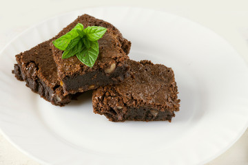 Delicious chocolate cake on a white plate decorated with a mint leaf. Homemade baking. Traditional...
